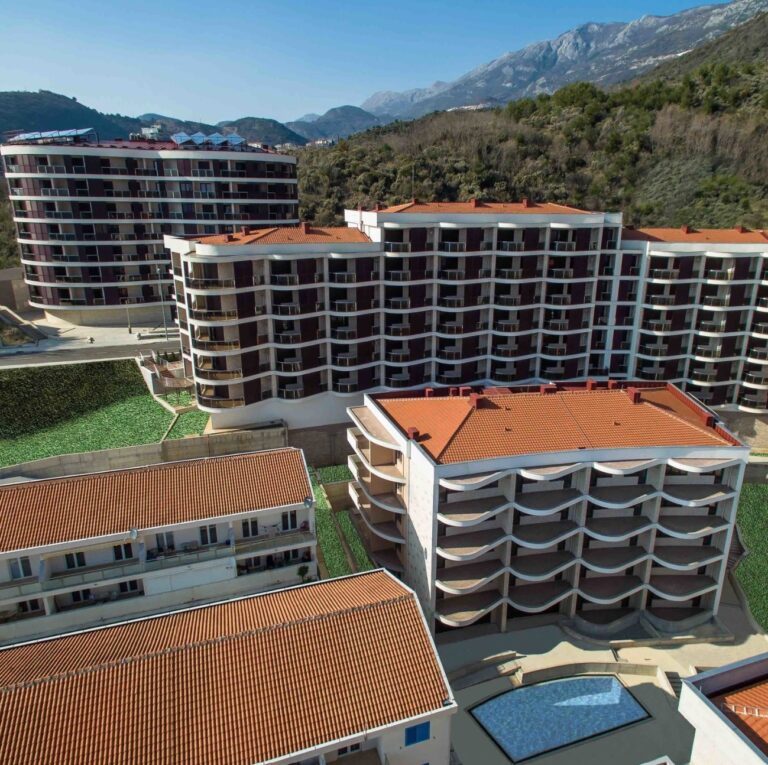 Complexos de apartamentos modernos com piscina, tendo como pano de fundo as montanhas. Arquitetura de telhado vermelho num ambiente pitoresco.