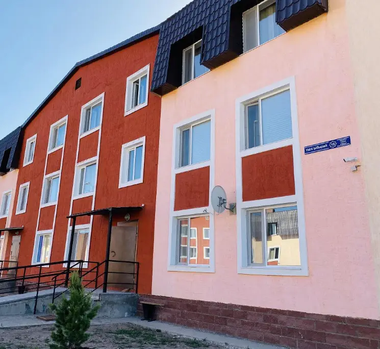 Een woongebouw met meerdere verdiepingen en een moderne rood-roze gevel aan Shiboldi Street.