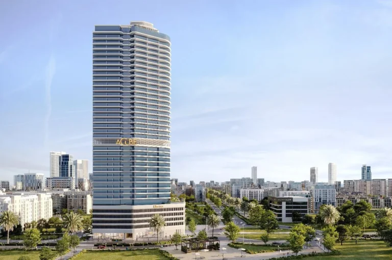 A tall modern skyscraper in the business center of the city against a backdrop of other urban architecture and a green park.