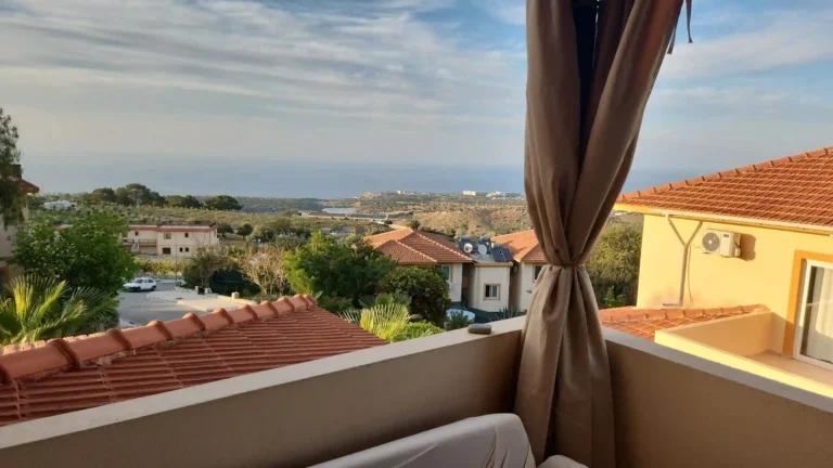 Der Blick vom Balkon auf die roten Dächer der Häuser und das Meer gegen den blauen Himmel und die grünen Bäume.