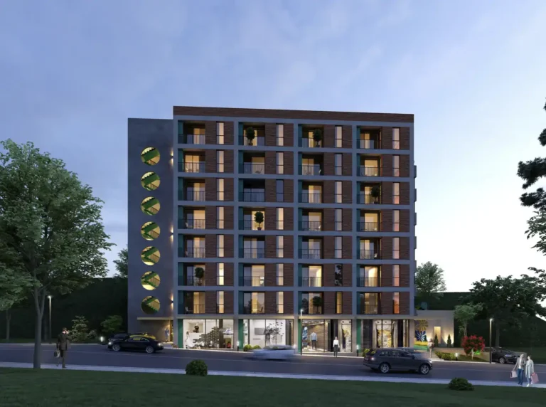 Modern apartment building in evening light with trees and cars in the foreground.