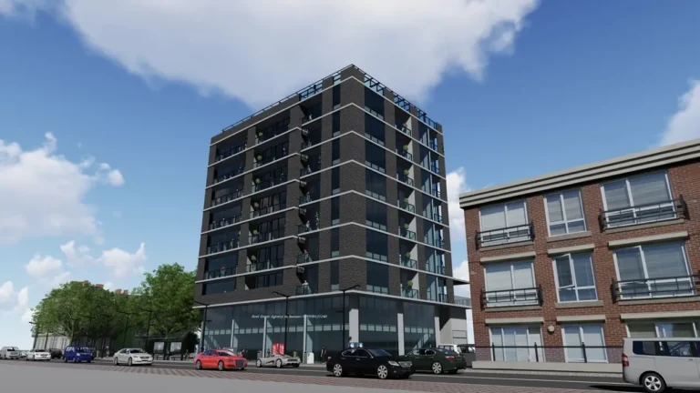 A modern eight-story building on a street with cars and green trees under a blue sky.