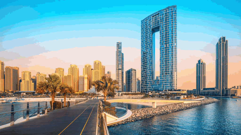 Modernos rascacielos de Dubai contra el cielo azul, palmeras frente al mar, reflejos en el agua.