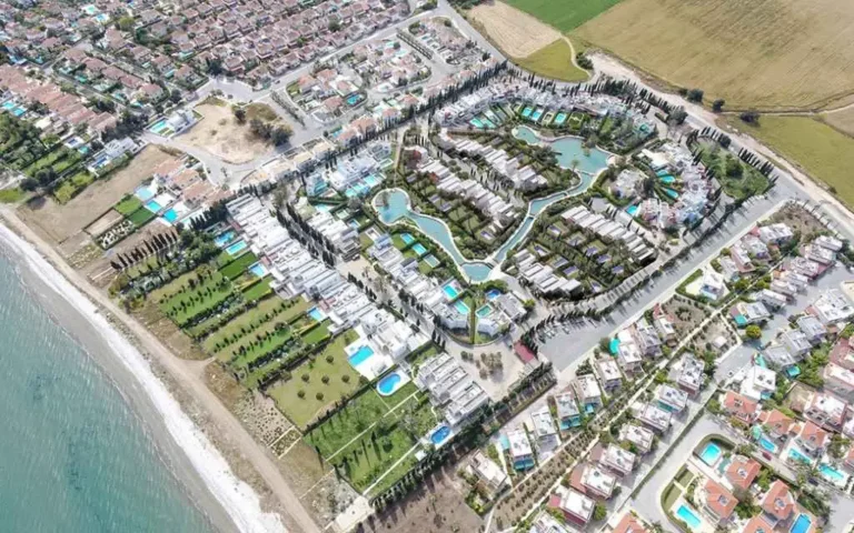 Vista aérea de una zona residencial con piscinas y zonas verdes cerca de la costa.