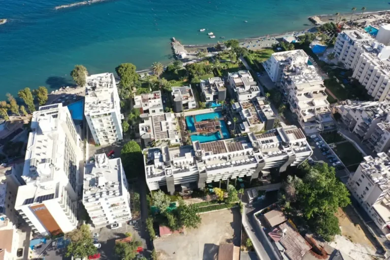 Vista de edificios costeros y playa desde dron en la ciudad, día soleado, piscina en el patio, árboles verdes.