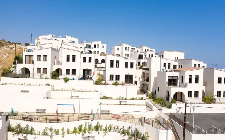 Un moderno complejo de casas blancas contra un cielo azul. Ventanas arqueadas y terrazas.