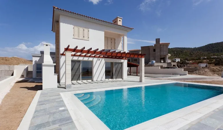 Casa blanca con terraza y piscina sobre un fondo de cielos azules y colinas. Lugar ideal para unas vacaciones de verano.