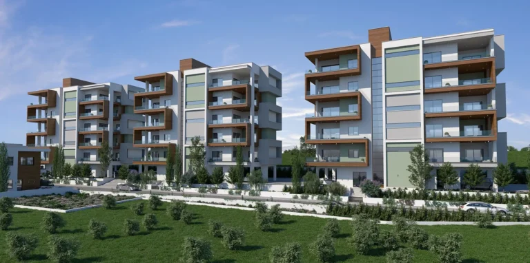 Modernus apartamentų kompleksas su balkonais ir žaliosiomis zonomis po žydru dangumi.