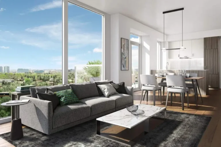 Modern living room with panoramic windows, gray sofa and dining area in a light interior.