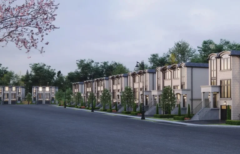 A row of modern townhouses with green space and evening lighting against a cloudy sky.