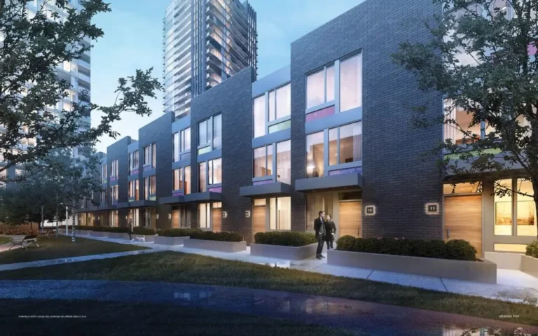 Modern townhouses with large windows and green space against a backdrop of high-rise buildings at night.