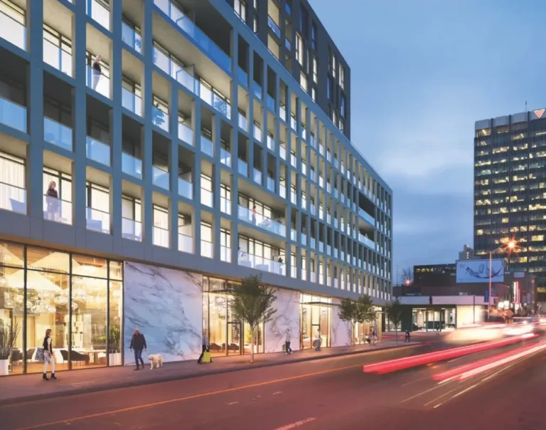 Street with modern building in the evening, people and dog on sidewalk, cars moving on the road.