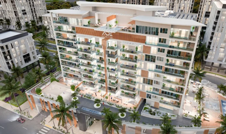 A modern residential complex with green balconies and terraces surrounded by palm trees in an urban environment.