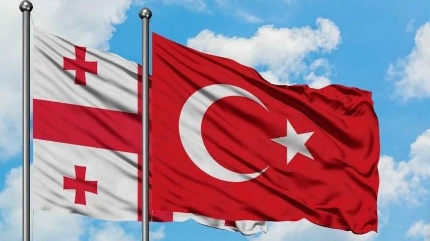 Paveikslėlis su Gruzijos ir Turkijos vėliavomis ir tekstu Gruzija ir Turkija: kur labiau apsimoka investuoti?