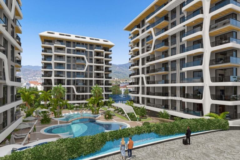 Modern residential complexes with swimming pool and green areas against the blue sky and mountains.