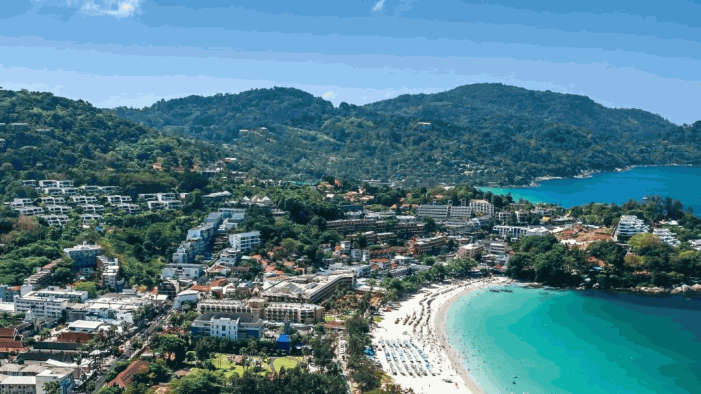 Panoramatický výhled na Phuket: zelené kopce, letoviska a pláž s tyrkysovým mořem. Oblíbené turistické letovisko v Thajsku.