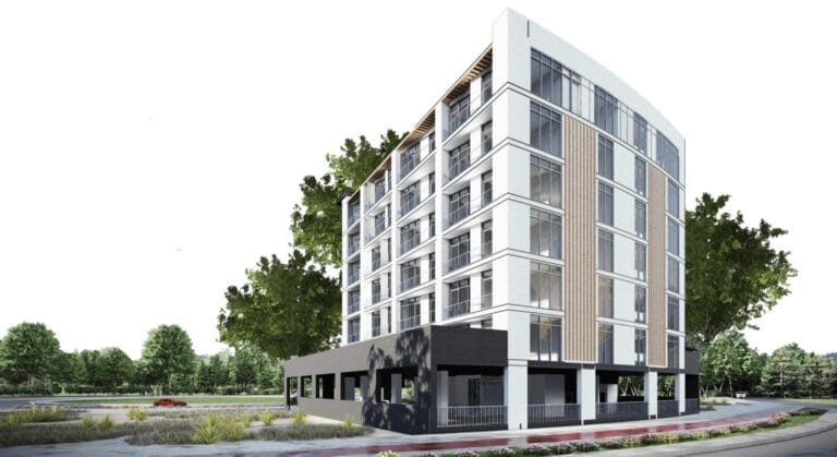 A modern apartment building with large windows and trees against a clear sky.