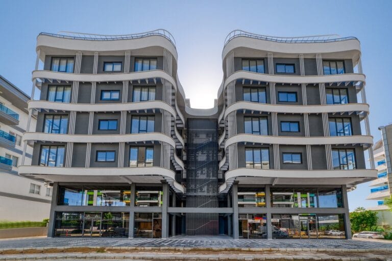 A modern residential building with an undulating facade against a blue sky.