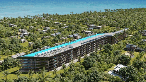 Un hotel moderno con una larga piscina en la azotea rodeada de vegetación y palmeras tropicales cerca de la playa.