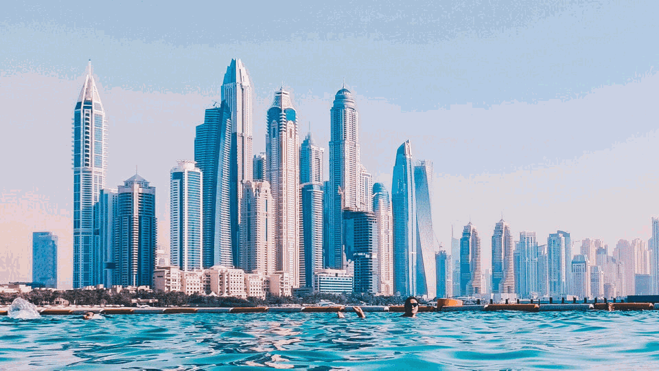 Modern skyscrapers of Dubai on the background of the sea and bright sky. Excursions and tours to Dubai.