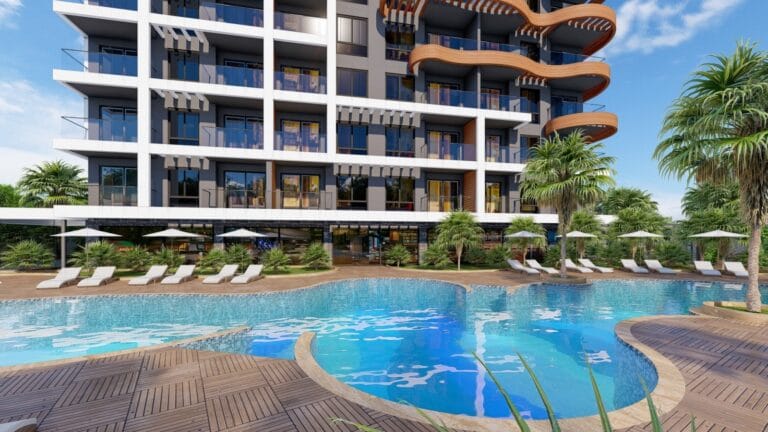 Modern apartments with balconies and swimming pool surrounded by palm trees and sun loungers in the resort.