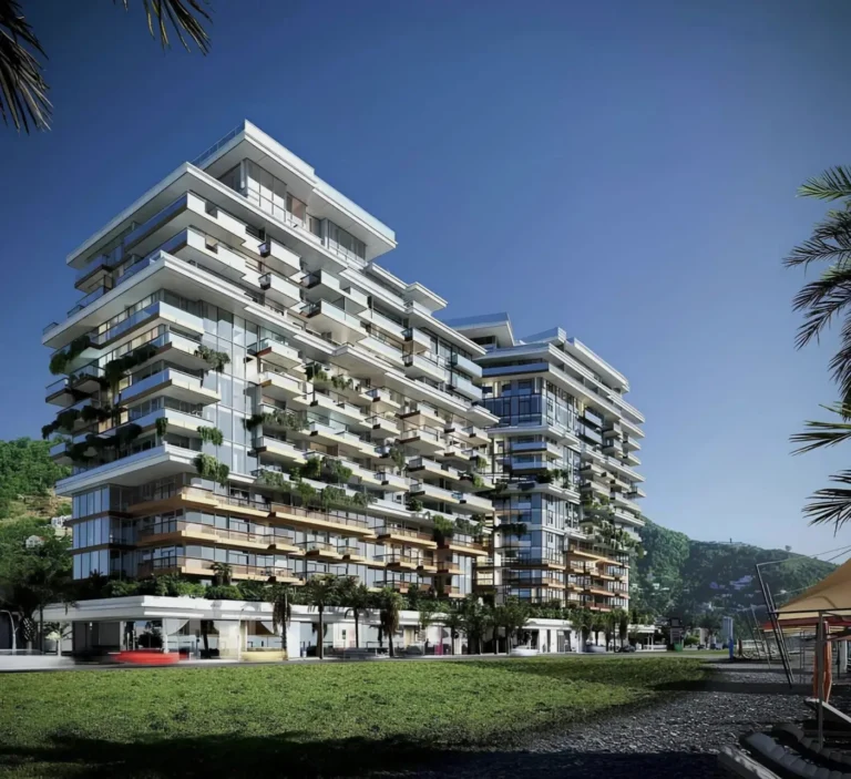 A modern building against the backdrop of nature and clear sky, surrounded by greenery and trees, by the sea.